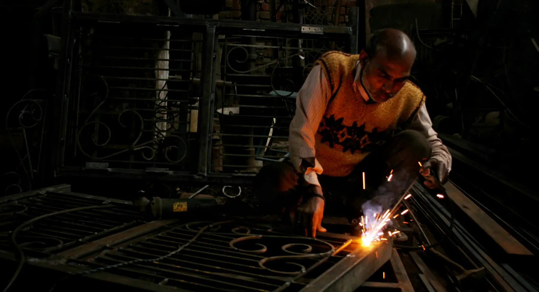 A fabricator holding a welding rod in a steel workshop