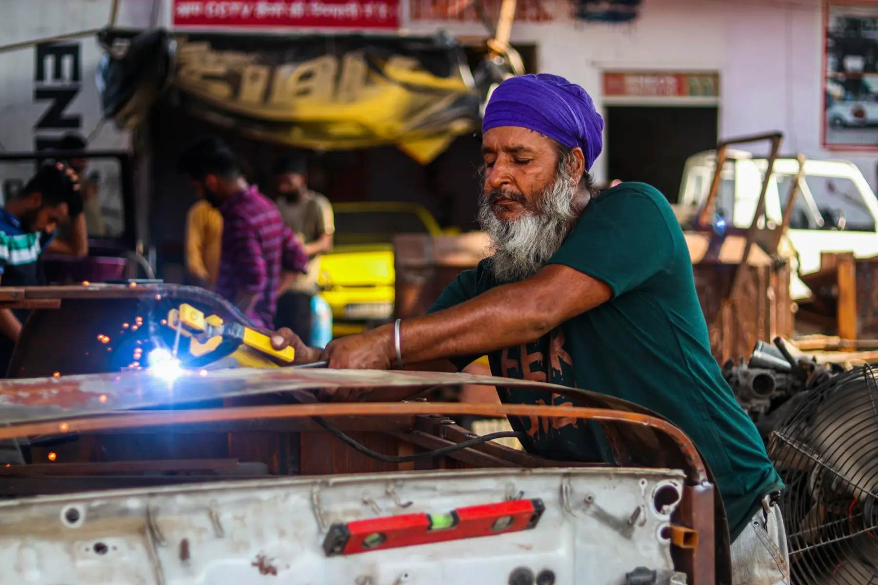 A welder at work in a busy metal workshop, sparks flying